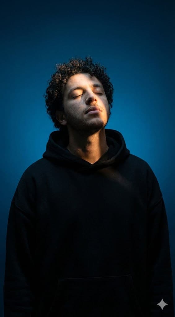 Surreal Cinematic Portrait Prompt – Oversized Black Hoodie, Dramatic Blue Lighting — Portrait AI art prompt example for Gemini and Stable Diffusion