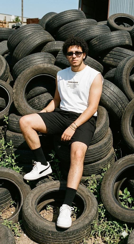 High-Impact Streetwear Fashion Editorial – Young Man on Industrial Tire Stack Outdoor Portrait — 3D AI art prompt example for Gemini and Stable Diffusion